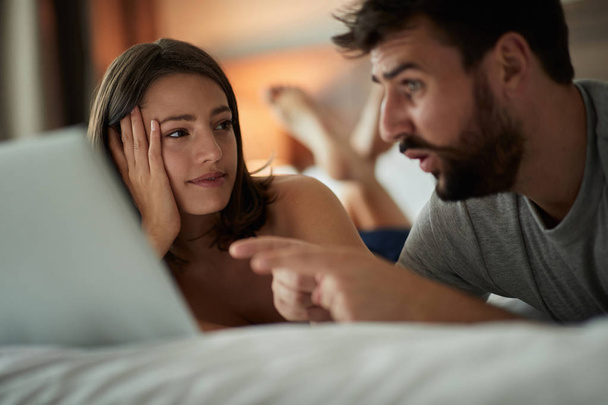 Giovane uomo e donna a letto utilizzando il computer portatile
 - Foto, immagini