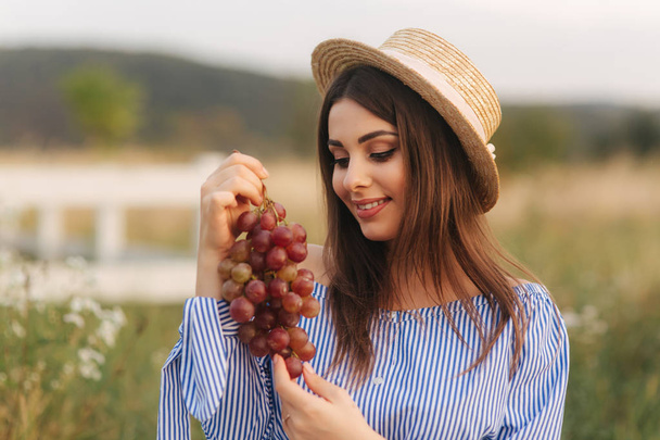 Beautiful pregnant woman show and eat red grapes. Healthy food. Fresh fruits. Happy woman smile - Photo, image