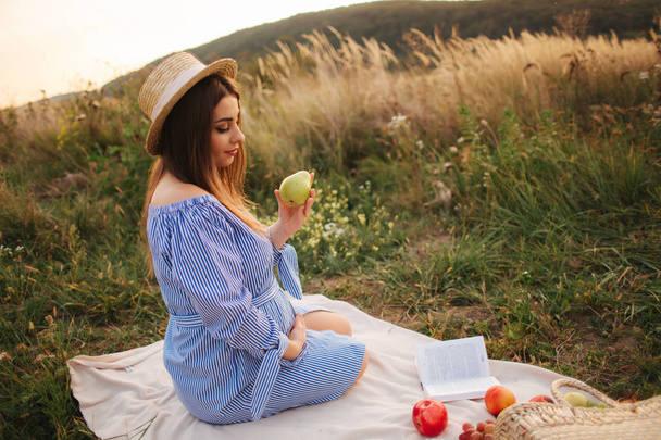 Όμορφη έγκυος γυναίκα δείξει και τρώνε κόκκινο αχλάδι. Υγιεινά τρόφιμα. Φρέσκα φρούτα. Ευτυχισμένη γυναίκα χαμόγελο - Φωτογραφία, εικόνα