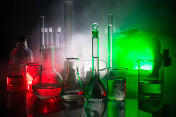 Pharmacy and chemistry theme. Test glass flask with solution in research laboratory. Science and medical background. Laboratory test tubes on dark toned background , science research equipment concept - Photo, Image