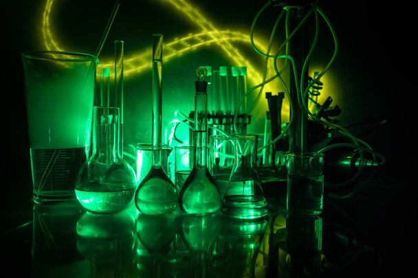 Φαρμακευτική και χημεία θέμα. Γυάλινη φιάλη δοκιμής με διάλυμα σε ερευνητικό εργαστήριο. Επιστήμη και ιατρικό υπόβαθρο. Εργαστηριακοί δοκιμαστικοί σωλήνες σε σκούρο τονισμένο φόντο, έννοια επιστημονικού ερευνητικού εξοπλισμού - Φωτογραφία, εικόνα