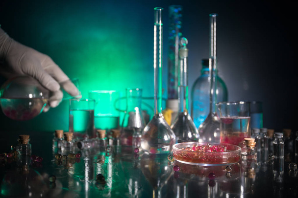 薬と化学のテーマ。研究室でのソリューションでガラスフラスコをテストします。科学と医学の背景。暗調を背景にした実験室試験管,科学研究機器コンセプト - 写真・画像