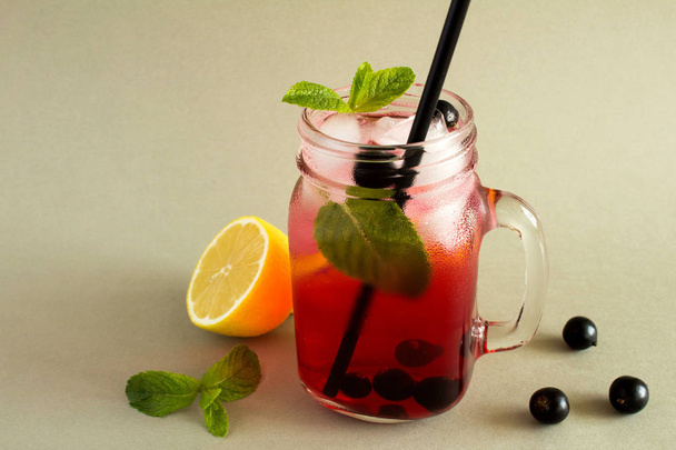 Cold lemonade with  black currant,lemon and mint on the  grey background - Photo, Image