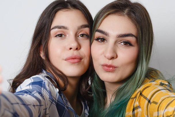 Close up lifestyle selfie portrait of two young positive woman having fun and making selfie, teenage hipster trendy clothes and fresh make up. - Zdjęcie, obraz