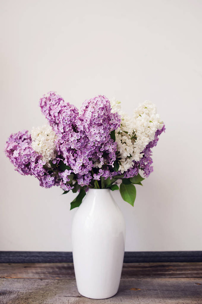Kytice šeříků v skleněná váza poblíž knihy a svíčku. Fialovými květy ve stylu vintage bílé pozadí. - Fotografie, Obrázek