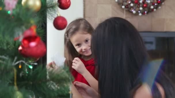 Mother and daughter decorate the Christmas tree for the new year. A woman with a child girl decorates the Christmas tree.  - Video