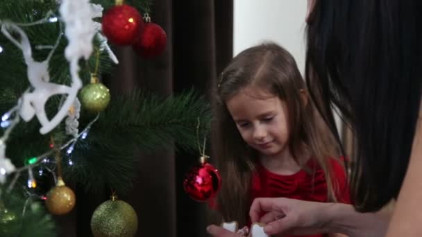 Mother and daughter decorate the Christmas tree for the new year. A woman with a child girl decorates the Christmas tree.  - Filmati, video