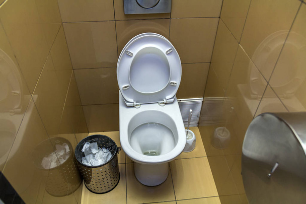 Interieur van eenvoudige toilet-toilet, bekijken van bovenaf. Witte keramische WC toilet-keramische bril op kopie ruimte achtergrond van licht beige tegel wanden en basis. Ontwerp en hygiëne concept. - Foto, afbeelding
