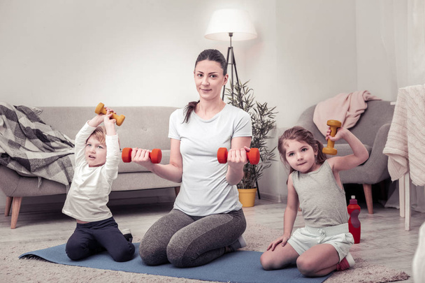 Children doing exercises with weights together with their mother - Фото, зображення