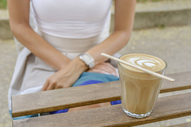 Latte sanat bir tahta masada oturan kız ile kahve fincanı - Fotoğraf, Görsel
