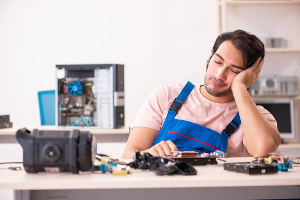 コンピュータを修理する若い男性請負業者   - 写真・画像