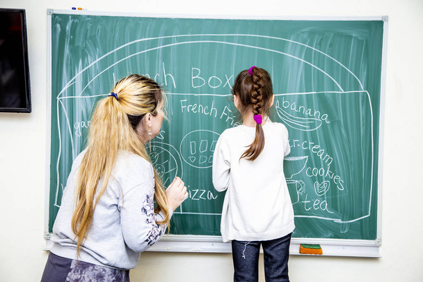 az angol órán a táblára írni a diák és a tanár - Fotó, kép