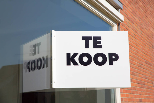 Placa de marketing branco na janela de casa com texto Te Koop ou Venda
 - Foto, Imagem