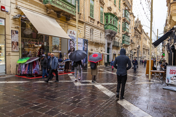 Valletta, Malta, on January 8, 2019. People go on Republic street during a rain - Valokuva, kuva