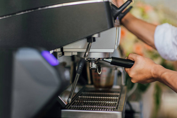 Утренний кофе, профессиональная бариста, шлифующая кофе в портафильтр, чтобы приготовить горячий эспрессо. Выбор фокуса
 - Фото, изображение