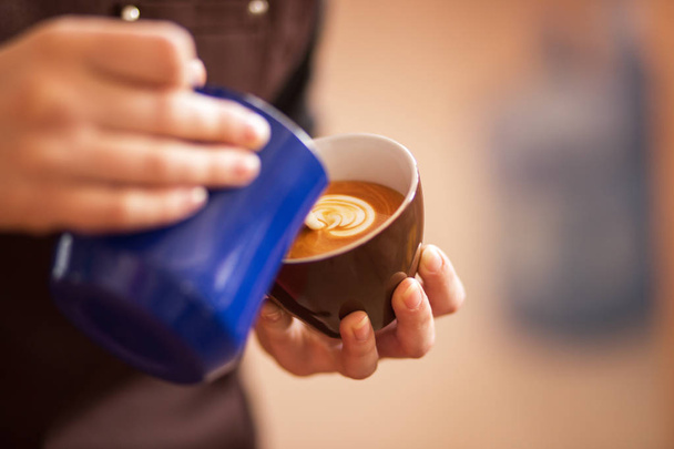 Nahaufnahme von Händen, die Milch einschenken und frischen Cappuccino zubereiten, Kaffeekünstler und Zubereitungskonzept, Morgenkaffee - Foto, Bild