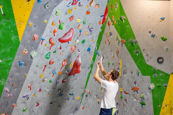climber explores and develops a route on a climbing wall in the boulder hall - Foto, Bild