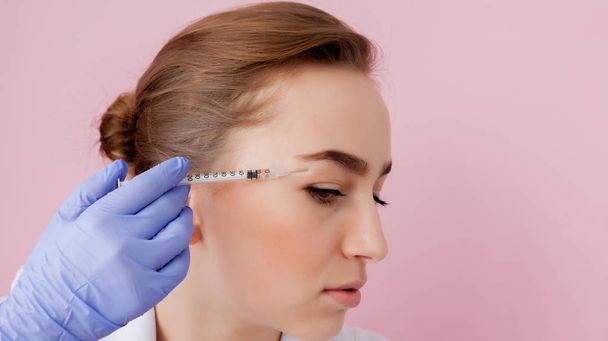 The doctor cosmetologist makes the Botulinotoxin injection procedure for tightening and smoothing wrinkles on the face skin of a beautiful, young woman in a beauty salon.Cosmetology skin care. - Foto, Bild