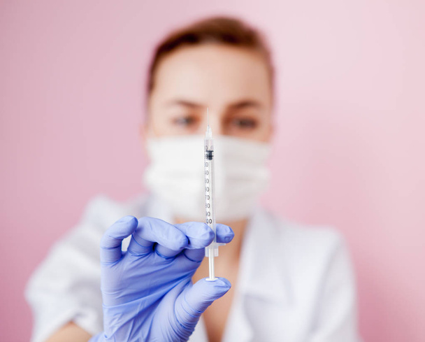 Close up nurse holding a syringe for injection, on pink background. - Fotoğraf, Görsel