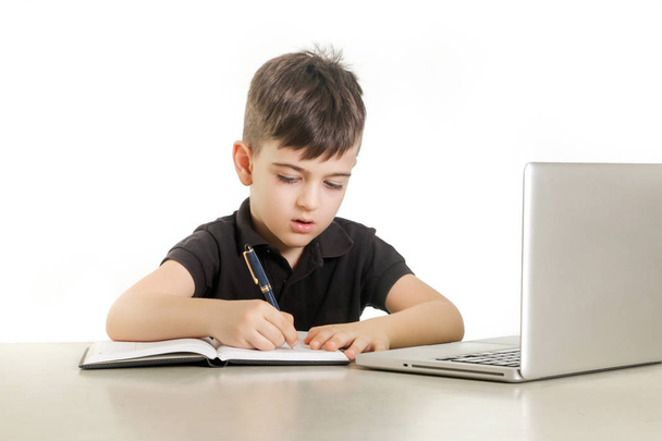 Jeune garçon prenant des notes devant un ordinateur portable
 - Photo, image