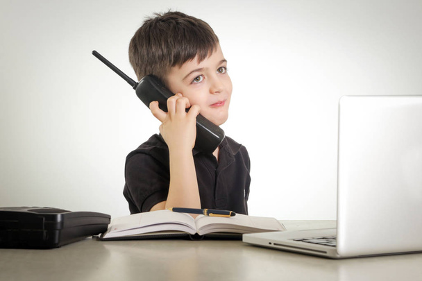 Young boy on the phone, in front of laptop - Foto, Imagen