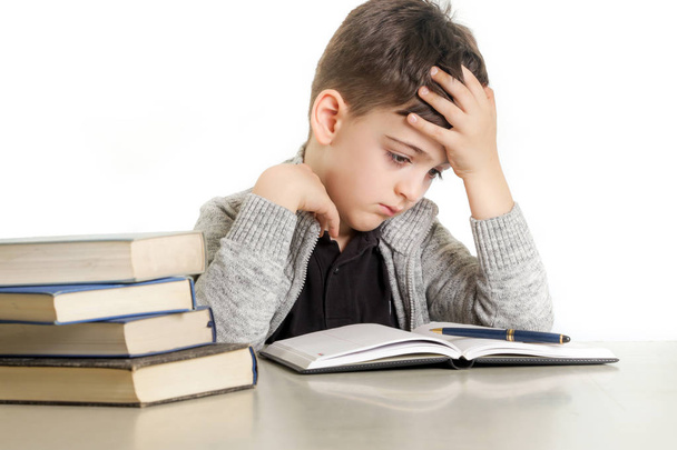 Studioporträt eines kleinen Jungen, der mit seinen Hausaufgaben kämpft - Konzept für Lernschwierigkeiten - Foto, Bild