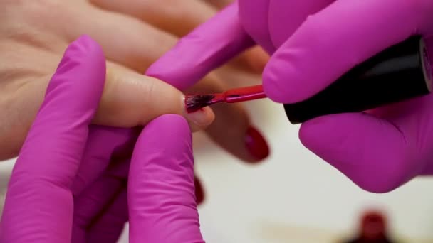 Specialist covers the nail of client by red varnish. Close up - Footage, Video