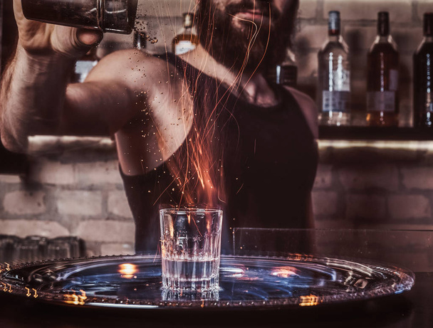 A bearded bartender pouring a cinnamon into a cocktail - Photo, Image