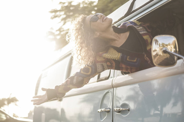 jonge vrouw uit voertuig genieten van wind tijdens reizen   - Foto, afbeelding