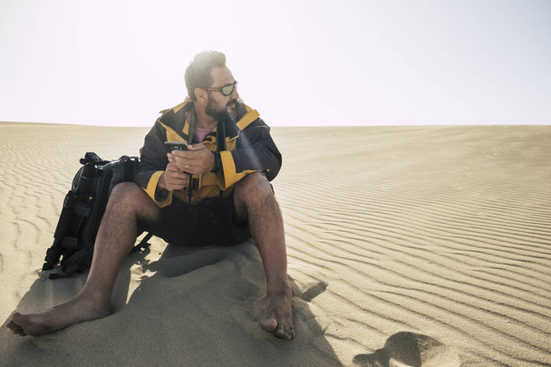 man barefoot sitting on sand during trekking at dessert  - Photo, Image