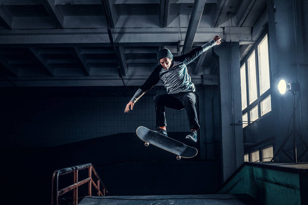 Young skateboarder performing a trick on mini ramp at skate park indoor.  - Фото, зображення