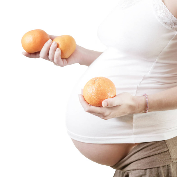 Mujer embarazada sosteniendo naranjas - toma de estudio
 - Foto, imagen