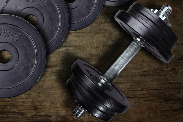 Dumbbell and weights on a wooden background. - Photo, Image