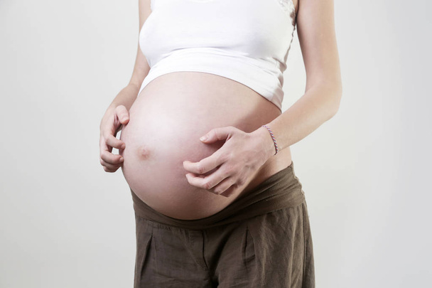 Pregnant woman scratches her belly - Zdjęcie, obraz