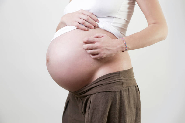 Pregnant woman scratches her belly - Fotografie, Obrázek