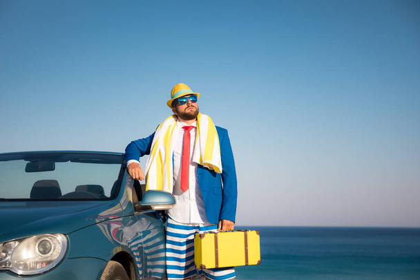 Successful young businessman on a beach. Man standing in the cabriolet classic car. Summer vacations and freedom travel concept - Foto, afbeelding