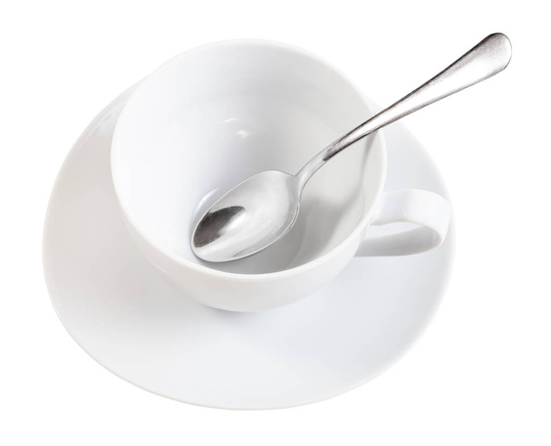 Beyaz arka planda izole edilmiş çay tabağında kaşıkla beyaz porselen bardağın üst görüntüsü - Fotoğraf, Görsel
