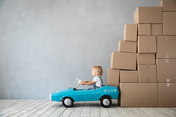 Happy child playing into new home. Kid driving toy car. Moving day concept - Fotoğraf, Görsel