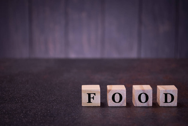 The word food on wooden cubes, on a dark background, light wooden cubes signs, symbols signs, business office, site content - Photo, Image