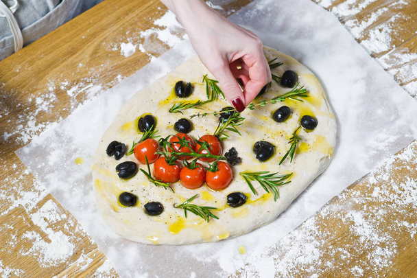 The chef prepares homemade Focaccia. Top view, wooden background - Photo, image