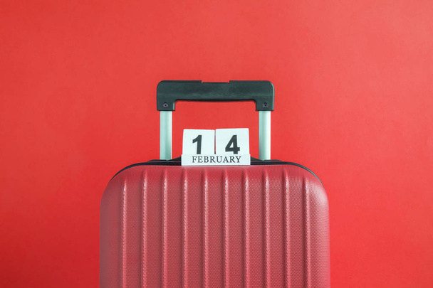 Valise avec 14 de février calendrier en bois sur fond rouge concept de voyage créatif minimal
. - Photo, image