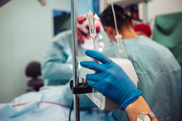 Verpleegkundige stelt de patiënten druppelaar op de achtergrond operatie - Foto, afbeelding