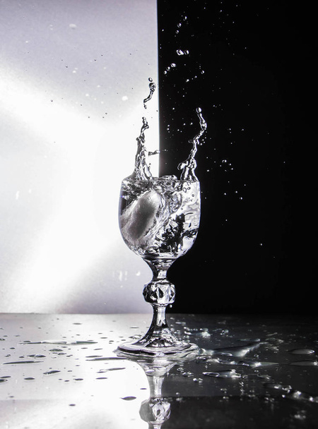 Läpinäkyvä lasi viinilasi jalalla roiskeella mustavalkoisella taustalla
 - Valokuva, kuva