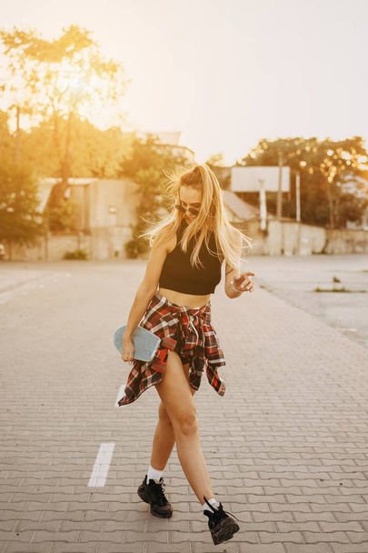 Young girl with a skateboard on a car park. - 写真・画像