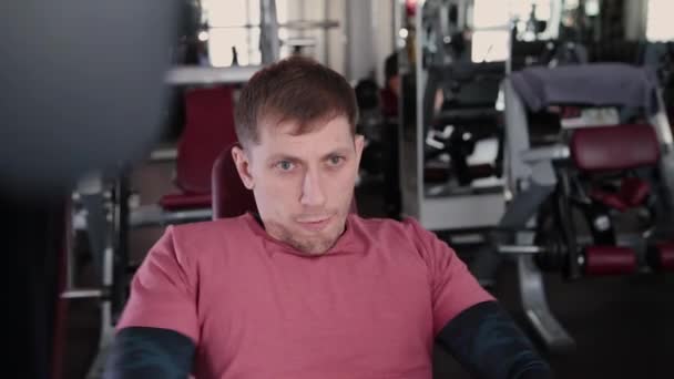 Athletic and attractive man trains pectoral muscles on a simulator in the gym - Filmagem, Vídeo