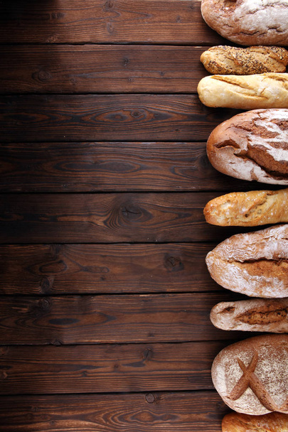 Sortimento de pão assado e pães em fundo de mesa de madeira. Conceito de cartaz de padaria
 - Foto, Imagem