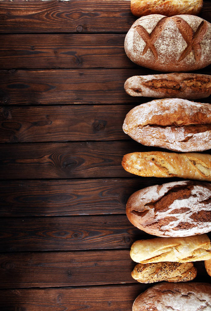 Sortiment von gebackenem Brot und Brötchen auf Holztischhintergrund. Bäckerplakat-Konzept - Foto, Bild