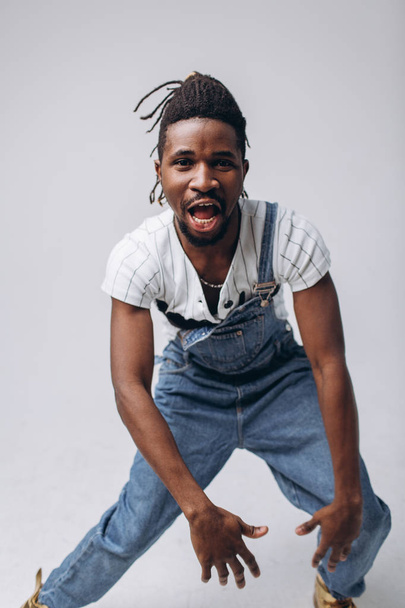 African American on a white background in jeans and a white T-shirt, emotions, emotional person - Valokuva, kuva