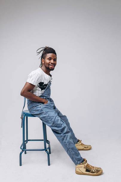 African American on a white background in jeans and a white T-shirt, emotions, emotional person - Fotó, kép