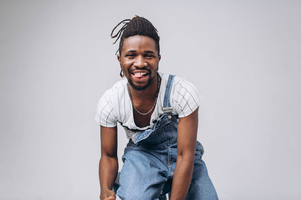 African American on a white background in jeans and a white T-shirt, emotions, emotional person - Fotoğraf, Görsel